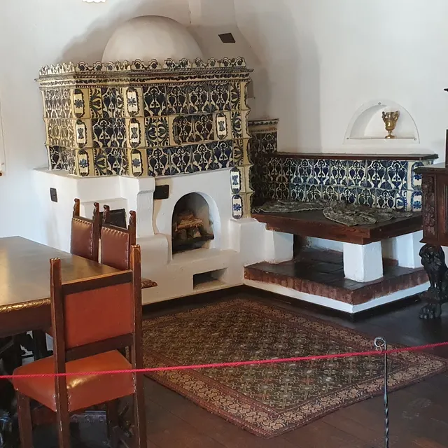 A tiled stove and table in a room at Bran Castle